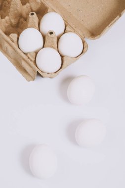 Beyaz yumurtalar parlak arka planda ve kahverengi yumurta tepsisinde. Seçici odaklanma. Kavram sahnesi. Üst görünüm. 