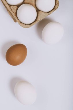 Parlak arka planda beyaz ve kahverengi yumurtalar ve kahverengi yumurta tepsisinde beyaz yumurtalar. Seçici odaklanma. Kavram sahnesi. Üst görünüm. 