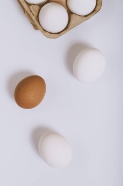 Parlak arka planda beyaz ve kahverengi yumurtalar ve kahverengi yumurta tepsisinde beyaz yumurtalar. Seçici odaklanma. Kavram sahnesi. Üst görünüm. 