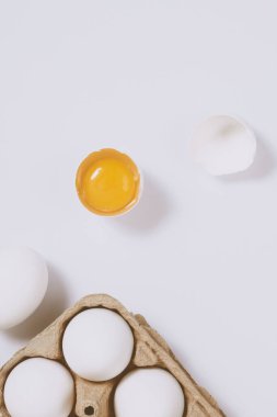 Yumurtanın yarısı kırılmış yumurta, yumurta tepsisinin yanında yumurta sarısı ve parlak bir arka plan. Seçici odaklanma. Kavram sahnesi. Üst görünüm