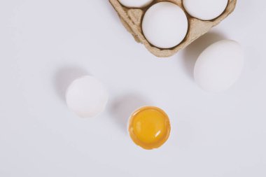 Yumurtanın yarısı kırılmış yumurta, yumurta tepsisinin yanında yumurta sarısı ve parlak bir arka plan. Seçici odaklanma. Kavram sahnesi. Üst görünüm