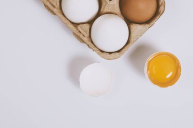 Yumurtanın yarısı kırılmış yumurta, yumurta tepsisinin yanında yumurta sarısı ve parlak bir arka plan. Seçici odaklanma. Kavram sahnesi. Üst görünüm