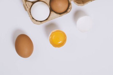 Yumurtanın yarısı kırılmış yumurta, yumurta tepsisinin yanında yumurta sarısı ve parlak bir arka plan. Seçici odaklanma. Kavram sahnesi. Üst görünüm