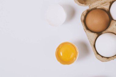 Yumurtanın yarısı kırılmış yumurta, yumurta tepsisinin yanında yumurta sarısı ve parlak bir arka plan. Seçici odaklanma. Kavram sahnesi. Üst görünüm