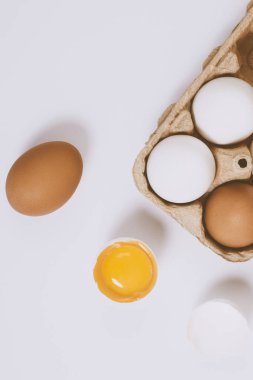 Yumurtanın yarısı kırılmış yumurta, yumurta tepsisinin yanında yumurta sarısı ve parlak bir arka plan. Seçici odaklanma. Kavram sahnesi. Üst görünüm