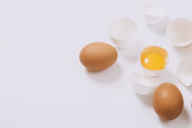 Kahverengi yumurtalar ve kırık beyaz yumurtalar. Parlak bir arka planda yumurta sarısı. Seçici odak.