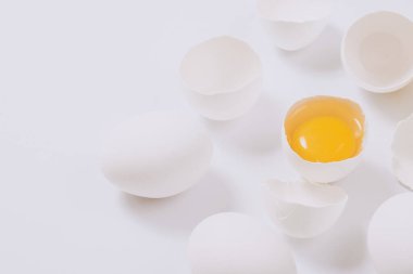 Tam beyaz tavuk yumurtası ve kırık yumurta. Parlak arka planda yumurta sarısı var. Seçici odak.