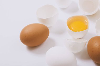 Tam beyaz ve kahverengi yumurta ve parlak bir arka planda yumurta sarısı. Seçici odak.