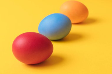 Sarı arka planda renkli boyanmış yumurtalar. Kavram sahnesi. Paskalya yumurtaları. Seçici odaklanma. Makro çekim.