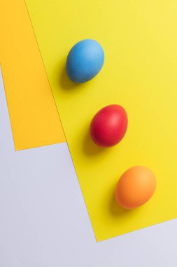 Parlak renkli geometrik arka planda renkli yumurtalar. Kavram sahnesi. Paskalya yumurtaları. Seçici odaklanma. Üst görünüm.