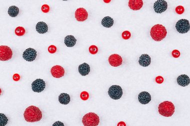 Açık dokulu masa üzerinde çeşitli taze böğürtlenler, üst manzara. Kırmızı ve siyah ahududu, yaban mersini ve kırmızı frenk üzümü. Desen, yakın çekim..