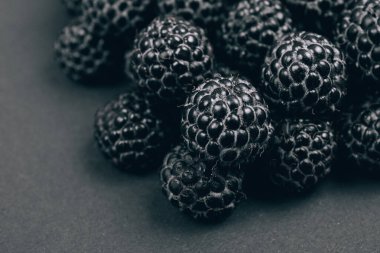 Gri arka planda taze olgun ve tatlı ahududu yığını. Siyah ahududu. Makro çekim.