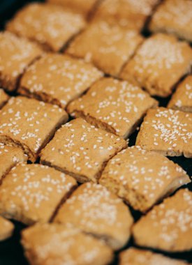 Square homemade cookies with sesame seeds.