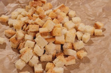Pieces of roasted white bread at the parchment paper. Close-up of delicious croutons.