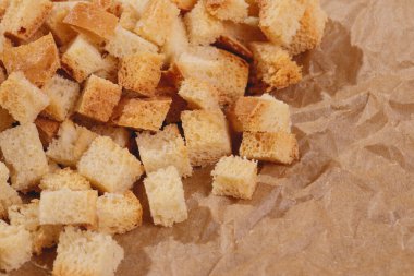 Pieces of roasted white bread at the parchment paper. Close-up of delicious croutons.