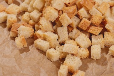 Pieces of roasted white bread at the parchment paper. Close-up of delicious croutons.