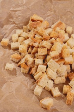 Pieces of roasted white bread at the parchment paper. Close-up of delicious croutons.