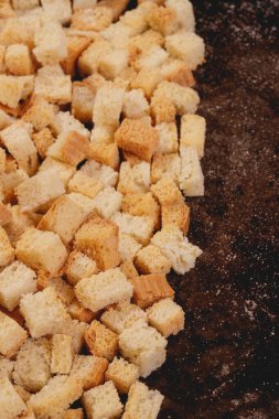Pieces of roasted white bread in the baking tray. Close-up of delicious croutons.