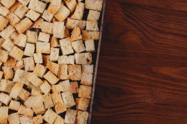 Pieces of roasted white bread in the baking tray on wooden table. Close-up of delicious croutons.