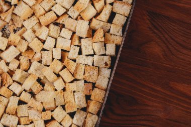 Pieces of roasted white bread in the baking tray on wooden table. Close-up of delicious croutons.