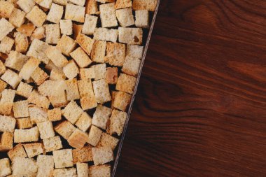 Pieces of roasted white bread in the baking tray on wooden table. Close-up of delicious croutons.
