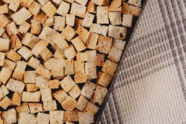 Pieces of roasted white bread in the baking tray on tablecloth. Close-up of delicious croutons.