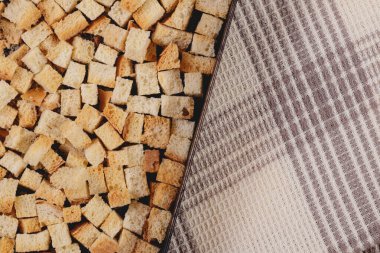 Pieces of roasted white bread in the baking tray on tablecloth. Close-up of delicious croutons.
