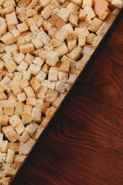 Pieces of roasted white bread in the baking tray on wooden table. Close-up of delicious croutons.