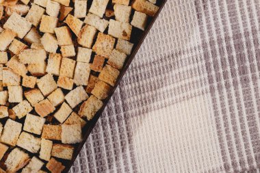 Pieces of roasted white bread in the baking tray on tablecloth. Close-up of delicious croutons.
