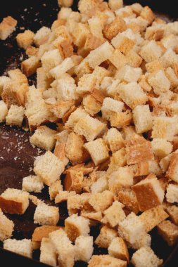 Pieces of roasted white bread in the baking tray. Close-up of delicious croutons.