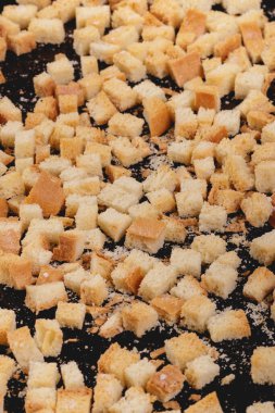 Koyu arkaplanda kavrulmuş beyaz ekmek parçaları. Lezzetli kızarmış ekmeklerin yakın çekimi..