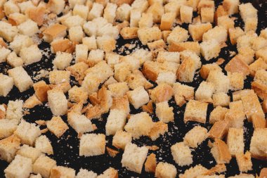 Koyu arkaplanda kavrulmuş beyaz ekmek parçaları. Lezzetli kızarmış ekmeklerin yakın çekimi..