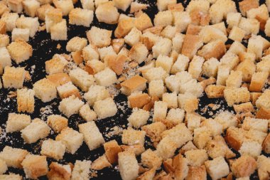 Koyu arkaplanda kavrulmuş beyaz ekmek parçaları. Lezzetli kızarmış ekmeklerin yakın çekimi..