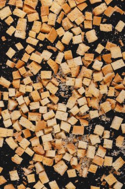 Pieces of roasted white bread on a dark background. Close-up of delicious croutons. Top view
