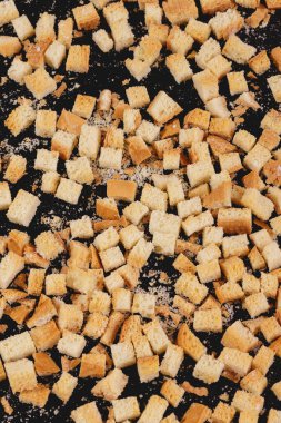 Pieces of roasted white bread on a dark background. Close-up of delicious croutons. Top view