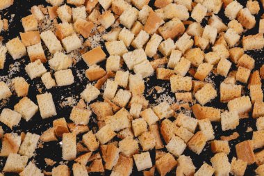 Pieces of roasted white bread on a dark background. Close-up of delicious croutons. Top view