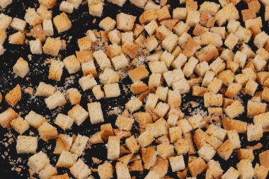 Pieces of roasted white bread on a dark background. Close-up of delicious croutons. Top view