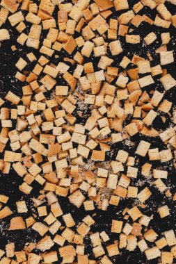 Pieces of roasted white bread on a dark background. Close-up of delicious croutons. Top view