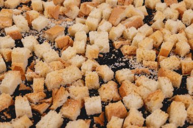 Koyu arkaplanda kavrulmuş beyaz ekmek parçaları. Lezzetli kızarmış ekmeklerin yakın çekimi..