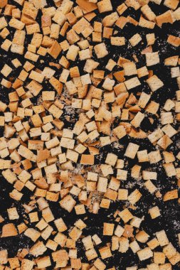 Pieces of roasted white bread on a dark background. Close-up of delicious croutons. Top view