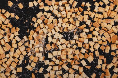Pieces of roasted white bread on a dark background. Close-up of delicious croutons. Top view