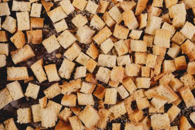 Pieces of roasted white bread on a dark background. Close-up of delicious croutons. Top view