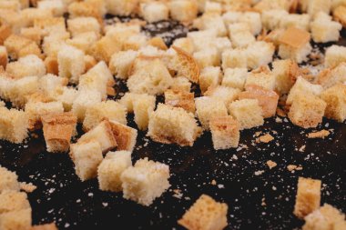 Koyu arkaplanda kavrulmuş beyaz ekmek parçaları. Lezzetli kızarmış ekmeklerin yakın çekimi..