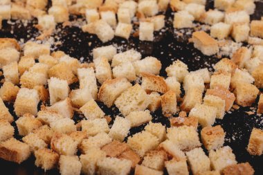 Koyu arkaplanda kavrulmuş beyaz ekmek parçaları. Lezzetli kızarmış ekmeklerin yakın çekimi..