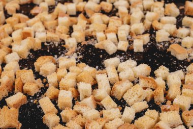 Koyu arkaplanda kavrulmuş beyaz ekmek parçaları. Lezzetli kızarmış ekmeklerin yakın çekimi..