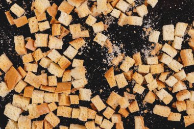 Pieces of roasted white bread on a dark background. Close-up of delicious croutons. Top view