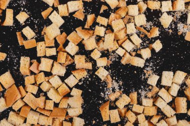 Pieces of roasted white bread on a dark background. Close-up of delicious croutons. Top view