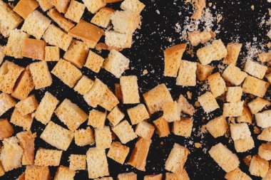 Pieces of roasted white bread on a dark background. Close-up of delicious croutons. Top view
