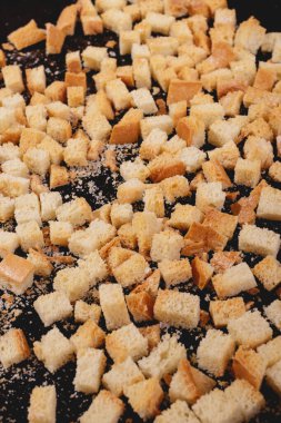 Koyu arkaplanda kavrulmuş beyaz ekmek parçaları. Lezzetli kızarmış ekmeklerin yakın çekimi..