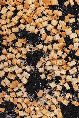 Pieces of roasted white bread on a dark background. Close-up of delicious croutons. Top view